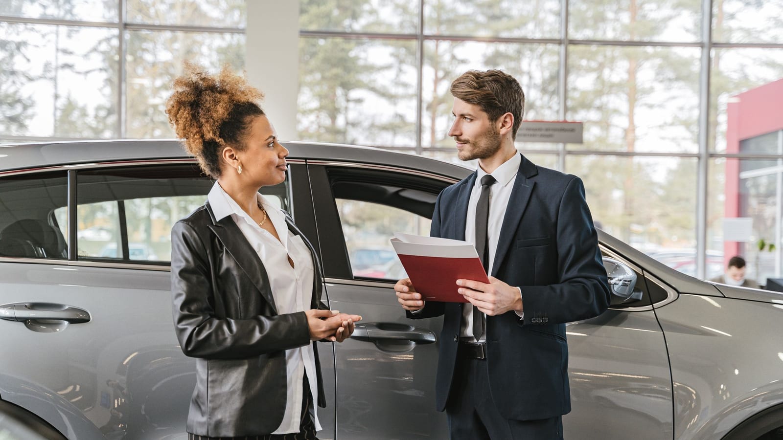 Cliente y asesor junto a un auto en la agencia